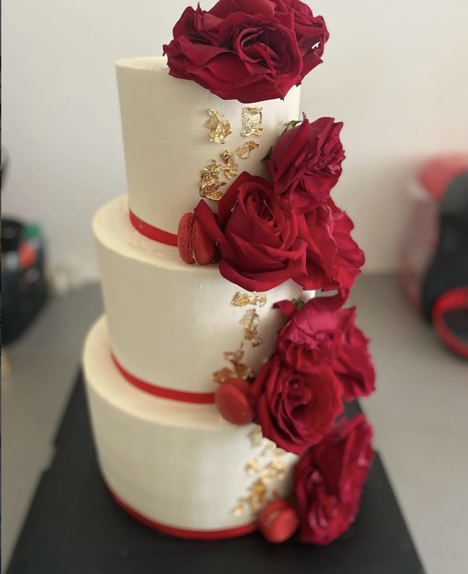 Gâteau de mariage aux roses rouges | Taasty Cakes Gâteau de mariage aux roses rouges — Une pièce montée blanche et élégante ornée de roses rouges, de macarons et de délicates touches dorées pour une réceptio | Taasty Cakes