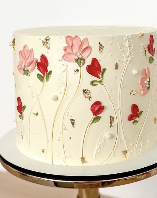 Gâteau floral rouge et rose | Taasty Cakes Gâteau floral rouge et rose — Un gâteau élégant aux motifs floraux, agrémenté de fleurs rouges et roses, de touches dorées et de finitions texturées. | Taasty Cakes