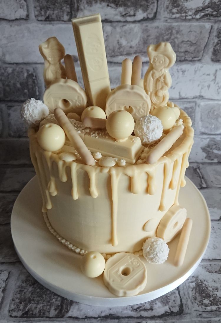 Gâteau chocolat blanc gourmand | Taasty Cakes Gâteau chocolat blanc gourmand — Un gâteau moelleux au chocolat blanc, décoré de bouchées, billes chocolatées, noix de coco et gourmandises assorties. | Taasty Cakes