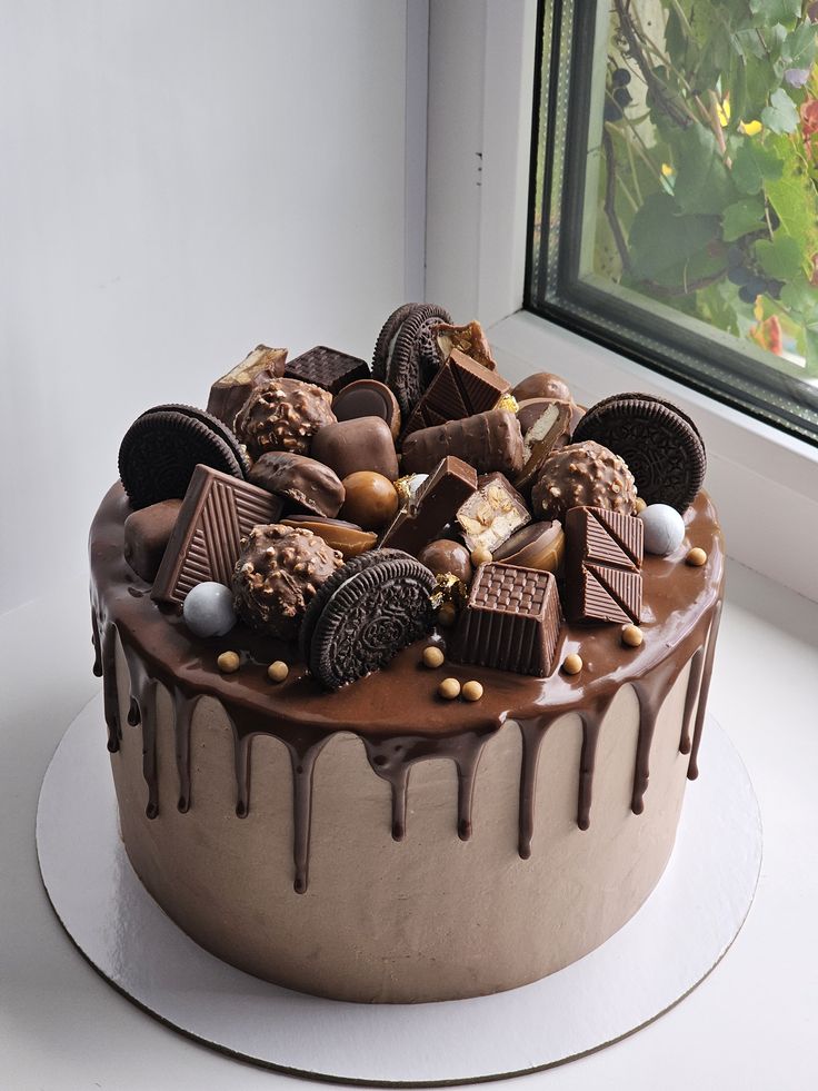 Drip Cake chocolat gourmand | Taasty Cakes Drip Cake chocolat gourmand — Un gâteau au chocolat recouvert d’un glaçage coulant et décoré de biscuits, barres chocolatées et bouchées gourmandes po | Taasty Cakes